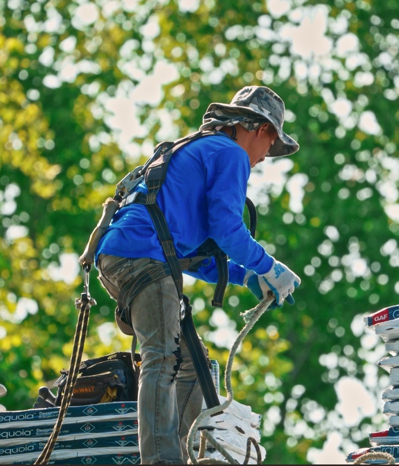Eminent Roofing installer in a safety harness staging GAF Sequoia shingles on a Tri-Cities roof