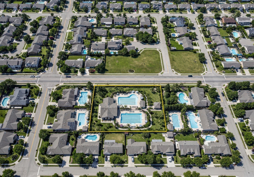 Aerial view of a residential neighborhood with asphalt roofs, yards, and a community pool