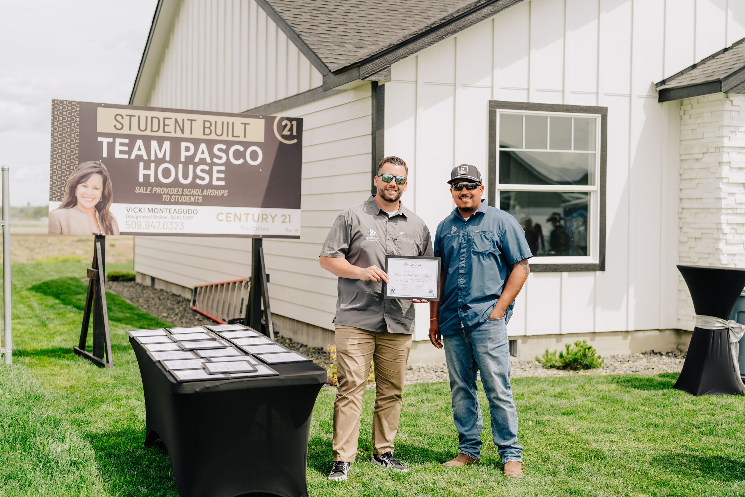 Eminent Roofing at the student-built Pasco Team House with a scholarship sale sign